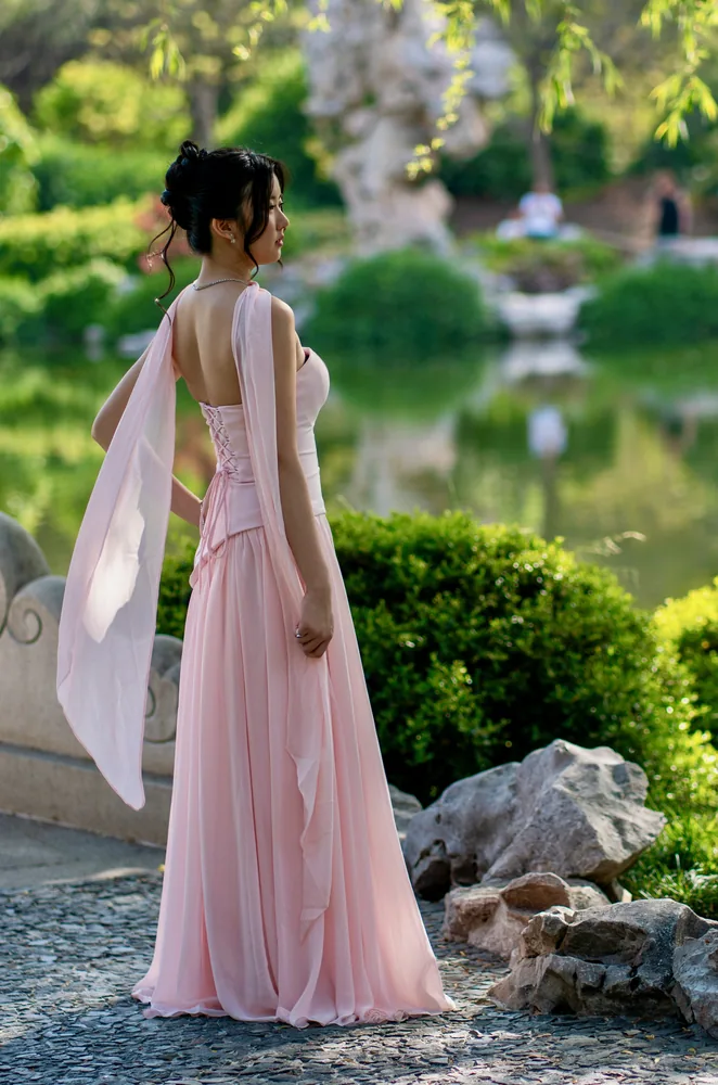 Woman in a flowing pink dress walking through a garden