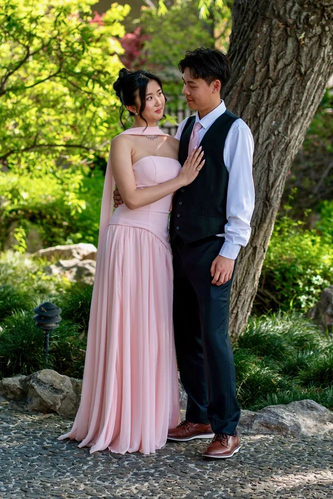 A formally dressed couple standing beneath a tree
