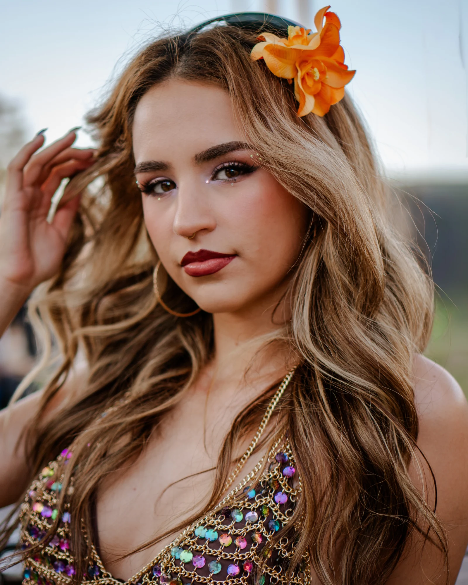 Editorial outdoor portrait of a woman wearing an orange flower in her hair
